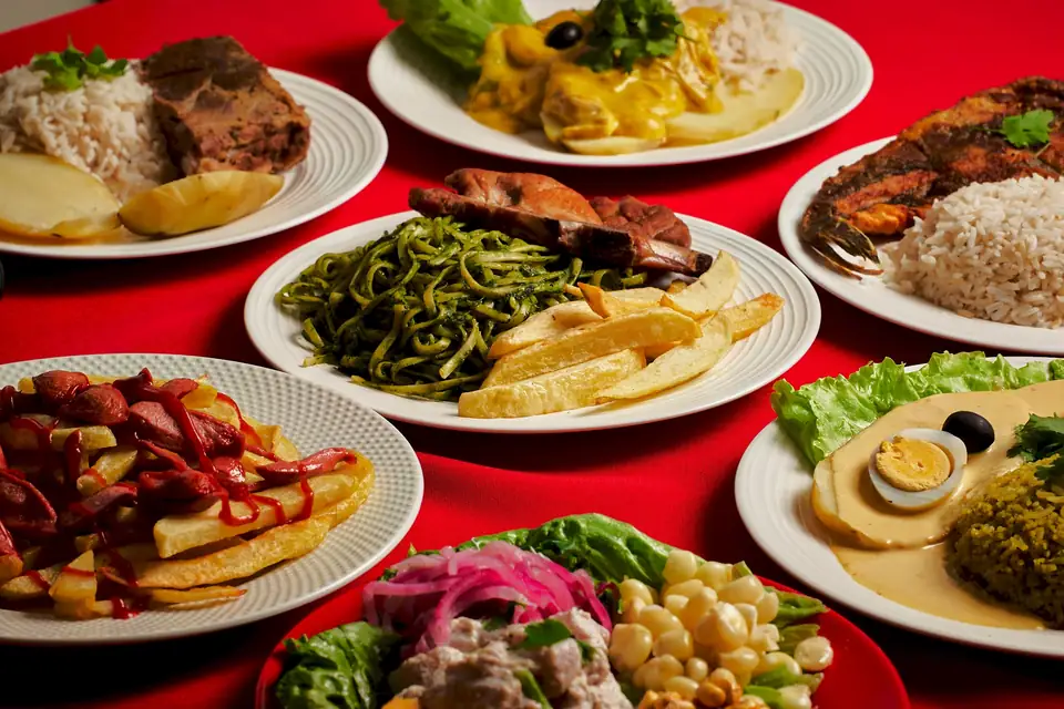 Mesa roja con platos caseros de El Ñaño: tallarín verde, pescado, salchipapas, ceviche y ají de gallina
