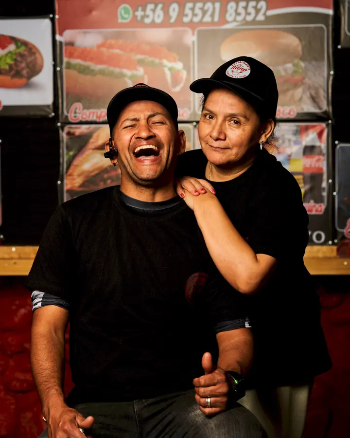 Dos integrantes del equipo de El Ñaño riendo frente al letrero del local